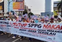 Massa Aliansi Masyarakat Lampung Dukung MBG AMAL MBG membawa spanduk "TUTUP SPPG NAKAL! YANG MENGKORUPSI JATAH MAKAN ANAK-ANAK SEKOLAH" saat aksi damai di Bandar Lampung, Senin 22/6/2026. Mereka menegaskan dukung program MBG dilanjutkan dan Presiden Prabowo, tapi desak koruptor MBG diproses hukum. FOTO : PROYEKSI.ID