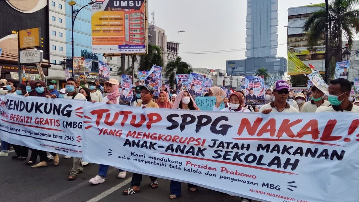 Massa Aliansi Masyarakat Lampung Dukung MBG AMAL MBG membawa spanduk "TUTUP SPPG NAKAL! YANG MENGKORUPSI JATAH MAKAN ANAK-ANAK SEKOLAH" saat aksi damai di Bandar Lampung, Senin 22/6/2026. Mereka menegaskan dukung program MBG dilanjutkan dan Presiden Prabowo, tapi desak koruptor MBG diproses hukum. FOTO : PROYEKSI.ID