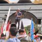 Seorang orator Aliansi Lampung Bersatu Awasi Kebijakan dan Anggaran berorasi menggunakan pengeras suara di depan gerbang Kantor DPRD Provinsi Lampung, Kamis 25/6/2026. 
