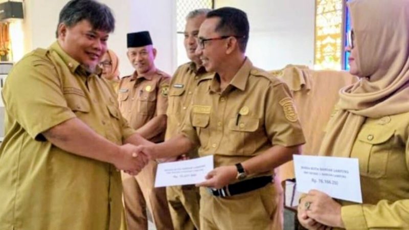 Plt Kepala Dinas Pendidikan dan Kebudayaan Kota Bandar Lampung M. Nur Ramdhan menyerahkan simbolis BOSDa SMP 2026 kepada perwakilan kepala sekolah. Pemkot mulai menyalurkan bantuan Rp300 ribu per siswa mulai 2 Juni 2026.