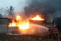 Dua petugas Damkar Lampung Selatan dan Pesawaran menyemprotkan air ke kobaran api yang membakar gudang CPO ilegal di Desa Negeri Sakti, Gedong Tataan, Pesawaran, Senin 8 Juni 2026 pukul 15.30 WIB. Api membumbung tinggi disertai asap hitam pekat. Kerugian ditaksir Ratusan juta rupiah. Foto: PROYEKSI.ID