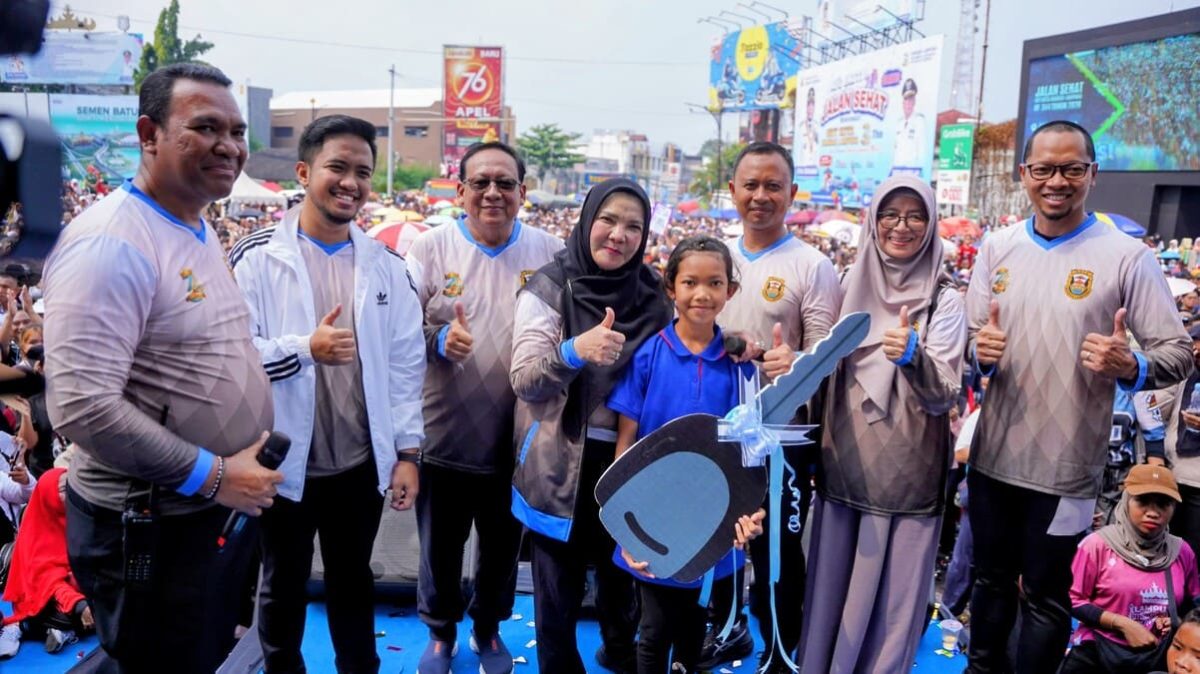 Wali Kota Bandar Lampung Eva Dwiana mendampingi Ernawati Ningsih dan anaknya saat penyerahan kunci replika mobil Daihatsu Sigra, hadiah utama jalan sehat HUT ke-344 Kota Bandar Lampung di Tugu Adipura, Minggu (28/6/2026). PROYEKSI.ID