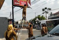 Petugas Bapenda Kota Bandar Lampung memasang stiker pemberitahuan kepada wajib pajak reklame yang menunggak di wilayah Rajabasa, Selasa 30/6/2026. Foto: Proyeksi.id