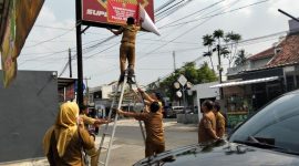 Petugas Bapenda Kota Bandar Lampung memasang stiker pemberitahuan kepada wajib pajak reklame yang menunggak di wilayah Rajabasa, Selasa 30/6/2026. Foto: Proyeksi.id