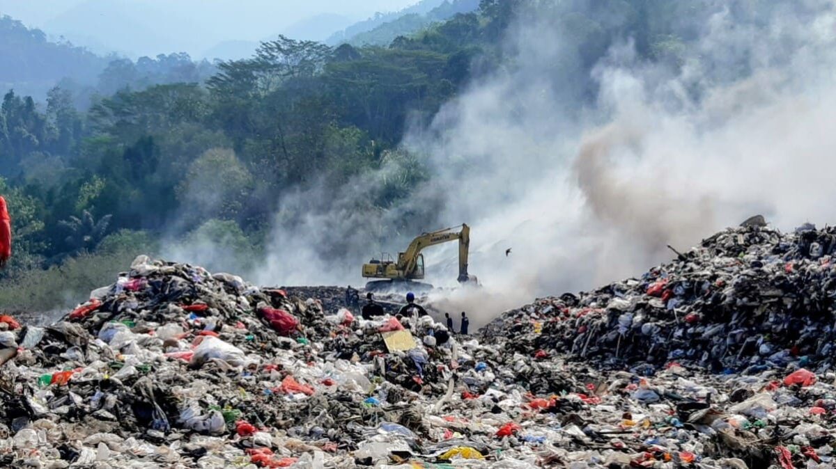 Petugas dan alat berat terlihat di tengah kepulan asap di Tempat Pemrosesan Akhir (TPA) Bakung, Kota Bandar Lampung, Kamis (9/7/2026). DLH menyiagakan tandon air di titik strategis sebagai langkah antisipasi kebakaran sampah saat musim kemarau. Foto: proyeksi.id