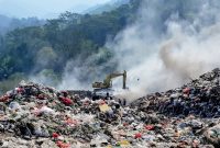 Petugas dan alat berat terlihat di tengah kepulan asap di Tempat Pemrosesan Akhir (TPA) Bakung, Kota Bandar Lampung, Kamis (9/7/2026). DLH menyiagakan tandon air di titik strategis sebagai langkah antisipasi kebakaran sampah saat musim kemarau. Foto: proyeksi.id