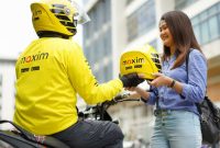 Seorang mitra pengemudi Maxim Bike menyerahkan helm kepada penumpang sebagai standar keselamatan layanan. Maxim resmi membuka kantor operasional di Bakauheni, Lampung Selatan, dengan layanan Bike, Car, hingga Food and Shop. (Foto: Dok. Maxim)