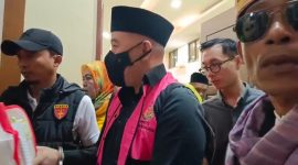  Terdakwa kasus dugaan korupsi SPAM, mantan Bupati Pesawaran Dendi Romadhona, berjalan keluar ruang sidang PN Tipikor Tanjungkarang dengan tangan diborgol, Jumat (3/7/2026). Seorang wartawan mengaku mengalami intimidasi saat merekam momen ini. Foto: ist