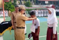 Kepala SMP Negeri 2 Bandar Lampung Abdul Khanif, M.Pd (tengah) mengalungkan tanda peserta kepada perwakilan siswa baru saat pembukaan Masa Pengenalan Lingkungan Sekolah (MPLS) Ramah Tahun Ajaran 2026/2027 di lapangan SMPN 2 Bandar Lampung, Senin (13/7/2026). MPLS Ramah berlangsung 13-17 Juli 2026 dengan mengedepankan pendekatan humanis, inklusif, dan anti perundungan. foto : istimewa