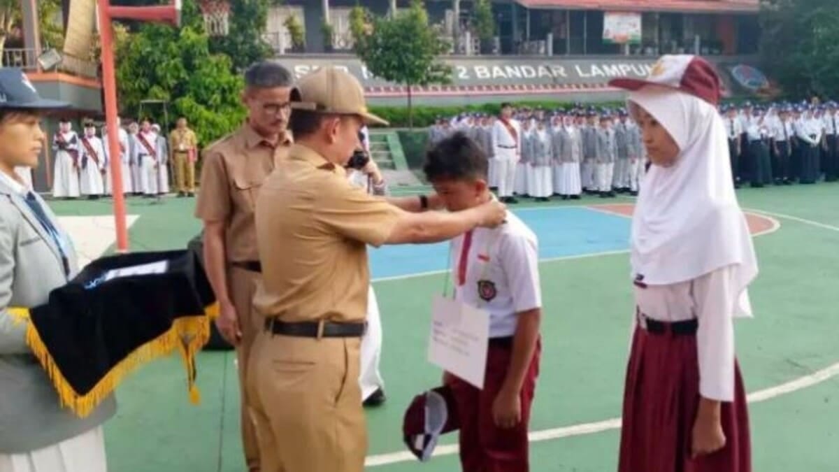 Kepala SMP Negeri 2 Bandar Lampung Abdul Khanif, M.Pd (tengah) mengalungkan tanda peserta kepada perwakilan siswa baru saat pembukaan Masa Pengenalan Lingkungan Sekolah (MPLS) Ramah Tahun Ajaran 2026/2027 di lapangan SMPN 2 Bandar Lampung, Senin (13/7/2026). MPLS Ramah berlangsung 13-17 Juli 2026 dengan mengedepankan pendekatan humanis, inklusif, dan anti perundungan. foto : istimewa
