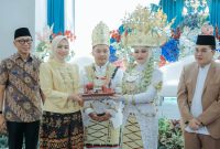 BANDAR LAMPUNG - Gubernur Lampung Rahmat Mirzani Djausal bersama Ketua TP PKK Provinsi Lampung Purnama Wulan Sari Mirza menyaksikan penyerahan mahar kepada salah satu pasangan peserta Nikah Massal Begawi Cinta Lampung 2026 di Ballroom Masjid Raya Al-Bakrie, Sabtu (25/7/2026). Sebanyak 31 pasangan mengikuti program pernikahan gratis yang digagas Pemprov Lampung dan Masjid Raya Al-Bakrie tersebut. Foto: istimewa