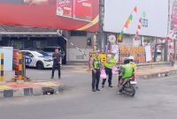 BANDAR LAMPUNG - Personel Pos Lantas Tugu Adipura Polresta Bandar Lampung membagikan paket makanan gratis kepada pengendara saat kegiatan Jumat Berkah di depan Pos Lantas Tugu Adipura, Jumat (17/7/2026). FOTO: PROYEKSI.ID
