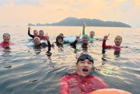 Anggota komunitas Perenang Antar Pulau berfoto di tengah laut Teluk Lampung, Sabtu (1/8/2026). Mereka menempuh jarak 2,3 km dari Pantai Mutun ke Pantai Kyoto, Pesawaran, di tengah rintik hujan dan ombak. [PROYEKSIID]
