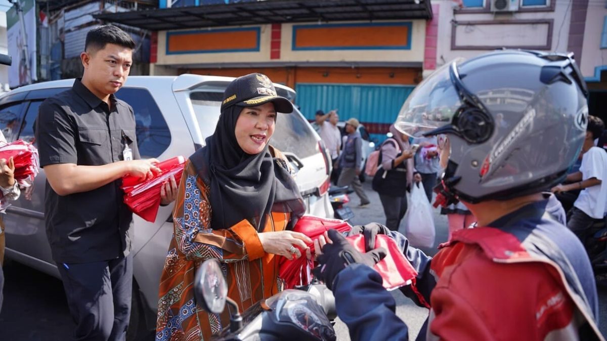 BANDAR LAMPUNG – Wali Kota Bandar Lampung Eva Dwiana membagikan bendera Merah Putih kepada pengendara motor di Jalan Yos Sudarso, Kecamatan Bumi Waras, Sabtu (8/8/2026). Sebanyak 10 ribu bendera dibagikan Pemkot untuk menyemarakkan HUT ke-81 Kemerdekaan RI. Foto: Proyeksi.id