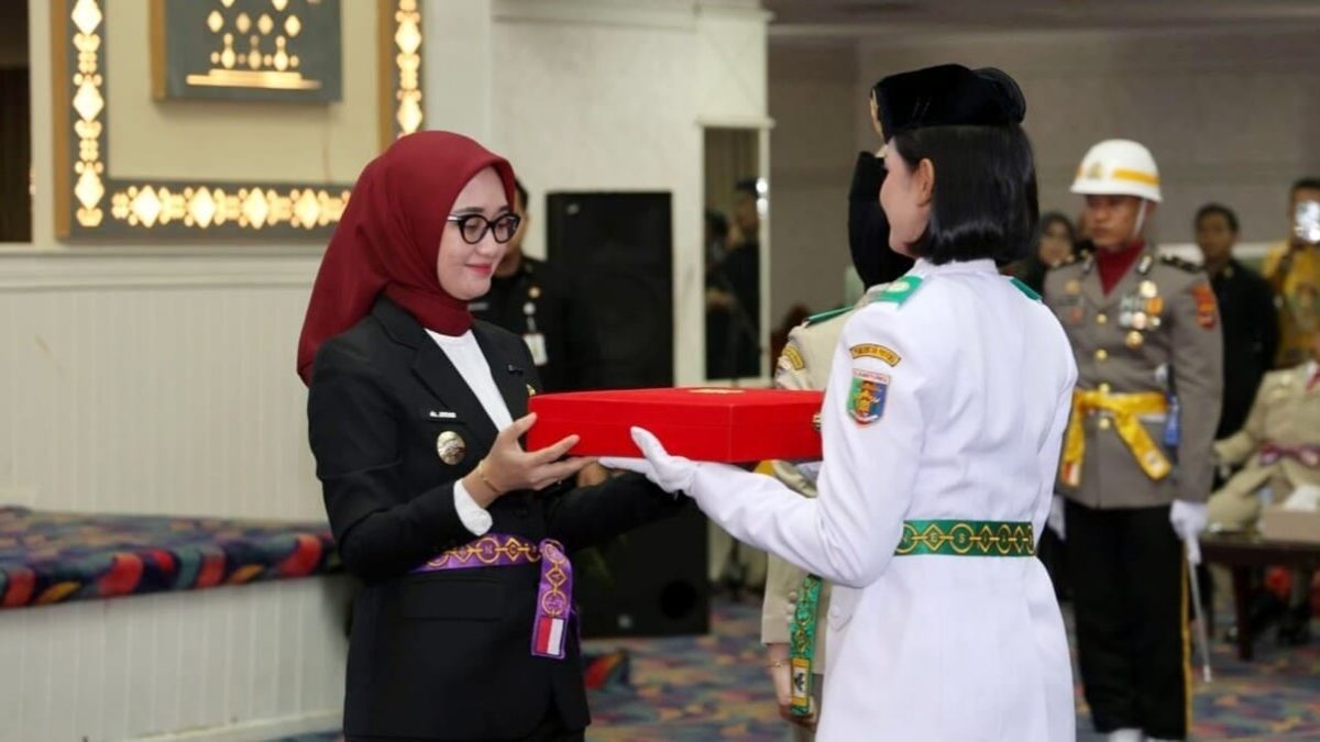 Wakil Gubernur Lampung Jihan Nurlela menyerahkan duplikat bendera pusaka kepada pemimpin Paskibraka Provinsi Lampung 2026 pada acara pengukuhan di Balai Keratun Lt. III Kantor Gubernur, Sabtu (15/8/2026). FOTO: PROYEKSI.ID